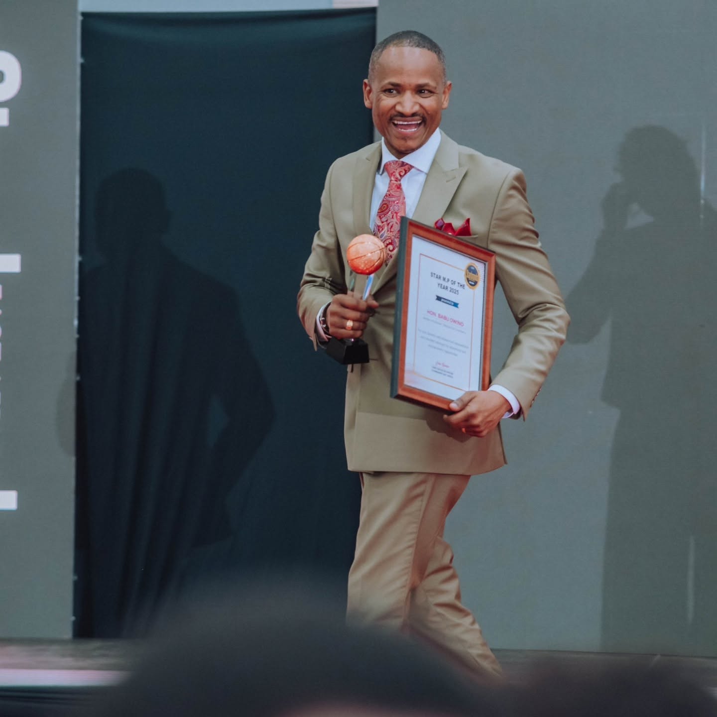 Hon. Babu Owino walking stage with award
