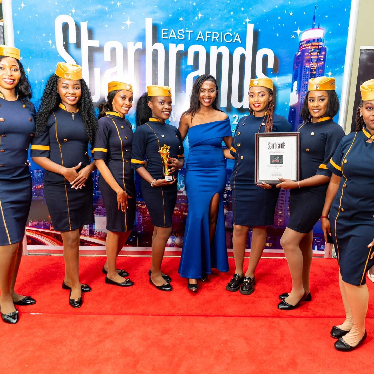 Honoree in royal blue gown on red carpet with hostess delegation